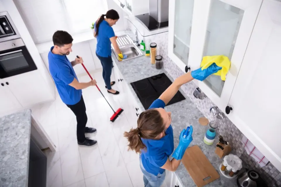 Tres professionals de neteja treballant alhora a la cuina d’un habitatge